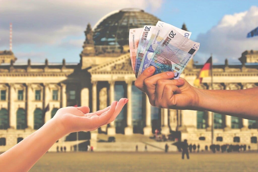 Hände, die Geld an eine andere Hand übergeben vor dem Berliner Parlament